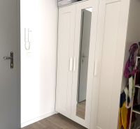 Built-in wardrobe with white doors and a mirror in a studio apartment.