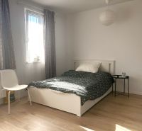 A bright room in a one-room apartment with a bed and a wooden decor floor.