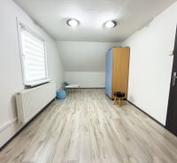 A room in a family house with a floor featuring a wooden decor and simple furniture.