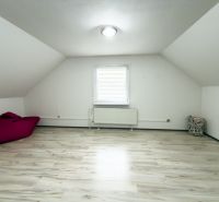 Attic room in a family house with a floor featuring a wooden decor and white walls.
