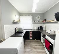 A kitchen in a family house with a wooden decor floor and gray walls.