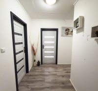A hallway in a family house with a wooden decor floor and decorative shelves.