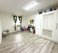 Children's room with a white wardrobe, window, and wooden decor flooring in a family house.