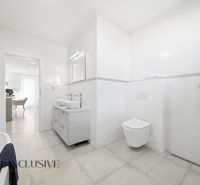 A bathroom with a shower, double sink, and toilet in a family house.