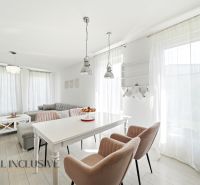 Interior of a family house with comfortable chairs, a dining table, and a sofa under large windows.