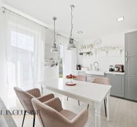 A kitchen in a family house with white furniture and wooden floor decor.