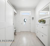 The entrance hall of a family house with white furniture and a wooden decor floor.