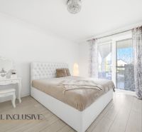 A bedroom in a family house with a bed, a mirrored table, and a floor with a wooden decor.