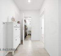 A hallway in a family house with a cabinet, wooden decor flooring, white walls.