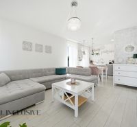 Living room with a corner sofa, table, and wooden decor flooring in a family house.