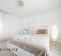 A bedroom with white furniture and a bed in a family house, floor with wooden decor.