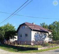 A family house in Margecany with a sloped roof, fenced, surrounded by greenery and a blue sky.
