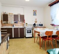 A kitchen in a family house with older furniture, a table, and chairs.