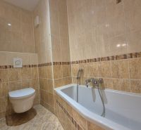 A bathroom with tiled walls and a bathtub in a 4-room apartment.