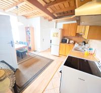 A kitchen in a 2-room apartment with a wooden decor floor and a wooden ceiling.