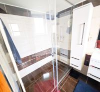 Bathroom in a 2-room apartment with a shower and a floor with a wooden decor.