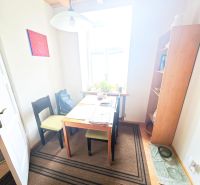 Dining area with a table, chairs, and shelves in a 2-room apartment.