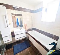 A bathroom in a 2-room apartment with a bathtub, shower, and white furniture.