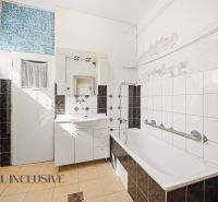 A bathroom in a family house with a white bathtub and mosaic tiles.