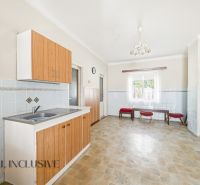 A kitchen with wooden cabinets and tiles, in a family house.