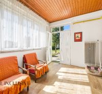 Interior of a family house with armchairs, large windows, and a wooden decor floor.