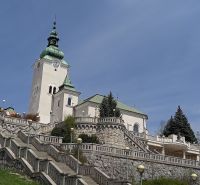 A church with a tower surrounded by a staircase and greenery in Ružomberok.