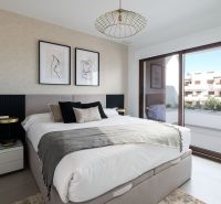 Bedroom in a 2-room apartment with a large window, art on the wall, and a comfortable bed.