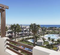 Balcony of a holiday apartment in Pulpí with a view of the pool and sea, surrounded by palm trees.