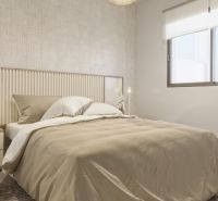 Bedroom in a holiday apartment with a bed, patterned wall, and large window.