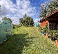 The garden of a family house in Bacúch with greenhouses and a gazebo surrounded by plants.