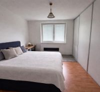 Bedroom with a large bed and a wooden decor floor in a family house.