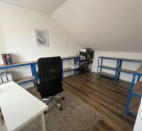 Office in a family house with a wooden decor floor, shelving system, and desk.