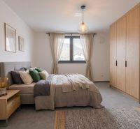 A bright bedroom with wooden furniture decor, gray accessories, and a large window.
