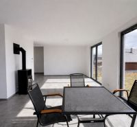 Living room in a family house with a fireplace, large windows, and black furniture.