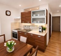 A kitchen in a one-room apartment with a wooden decor and simple furnishings.