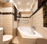 Bathroom with a bathtub, modern tiles, and a toilet in a studio apartment.