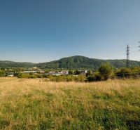 A landscape with a grassy plot and electric poles on Partizánska Street, Banská Bystrica. Plots - residential.