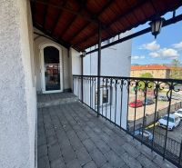 A balcony with an iron railing and a view of a parking lot in Banská Bystrica. Unusual properties.
