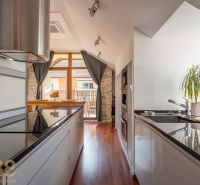 A kitchen in a 3-room apartment with a wooden decor floor, bright, with a plant and a cooktop.