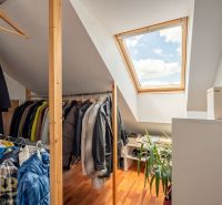 Attic wardrobe with a wooden decor floor in a 3-room apartment with a skylight.