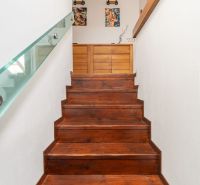 Stairs with a wooden decor floor and glass railing in a 3-room apartment.