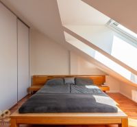 A bedroom in a three-room apartment with a wooden decor floor and skylights.