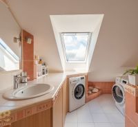 A bathroom in a 3-room apartment with a washing machine, a skylight, and white tiles.