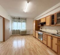 A kitchen in a family house with a light-colored kitchen unit and a wooden-patterned floor.