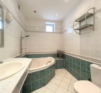 A bathroom in a family house with a bathtub, sink, mirror, and toilet.