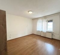 A room in a family house with a wooden decor floor and windows with white curtains.