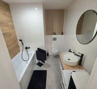 A bathroom in a 2-room apartment with a bathtub, black accessories, and tiles.
