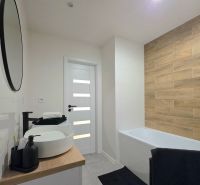 Bathroom in a 2-room apartment with a bathtub and a floor with a wooden decor.