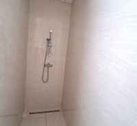 Shower enclosure in the office with tiles and a stainless steel shower.