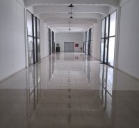 A spacious hallway in offices with a shiny floor and glass walls.